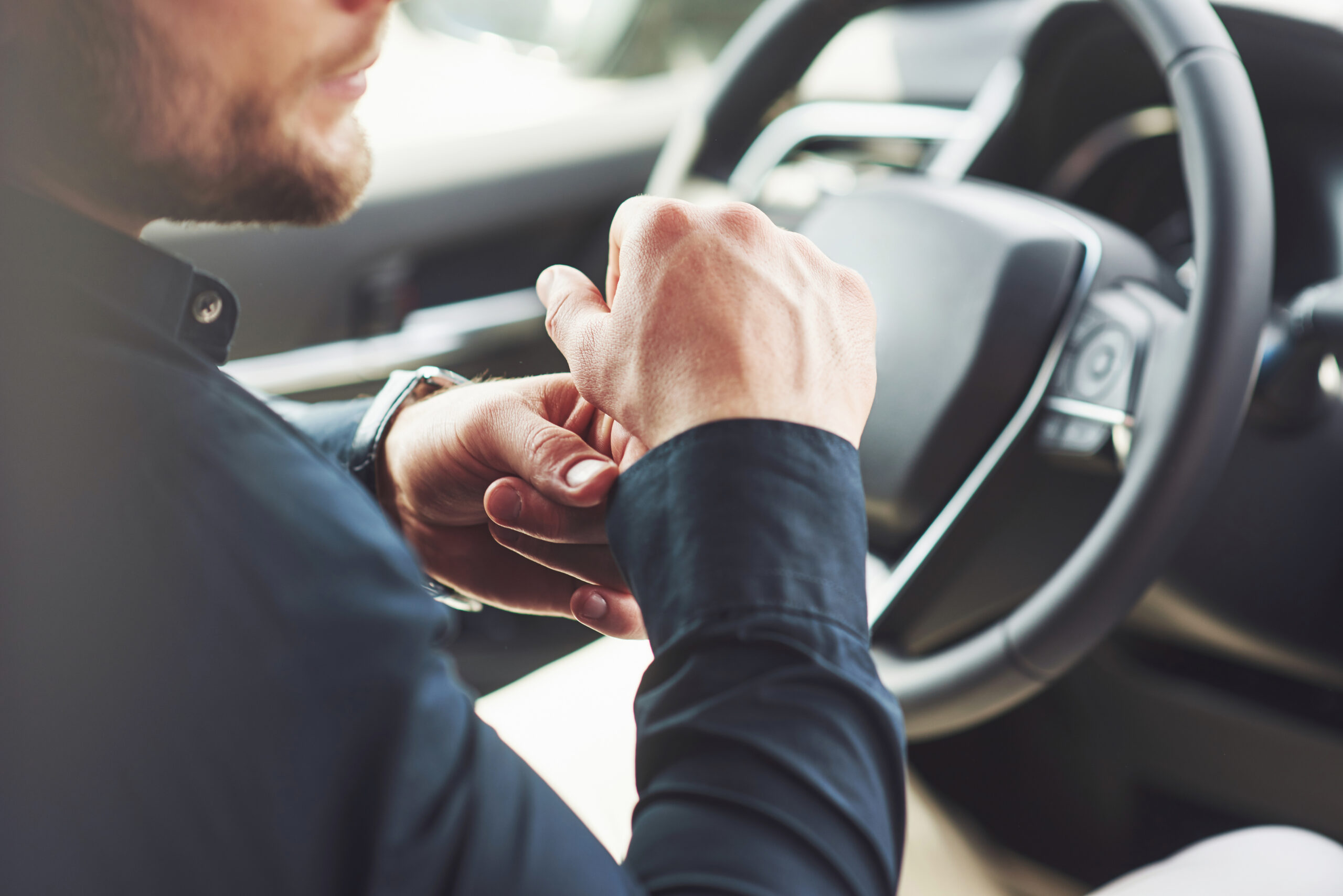 A businessman rides his car, moves on the wheel. Hand with watch A businessman rides his car, moves on the wheel. Hand with watch.