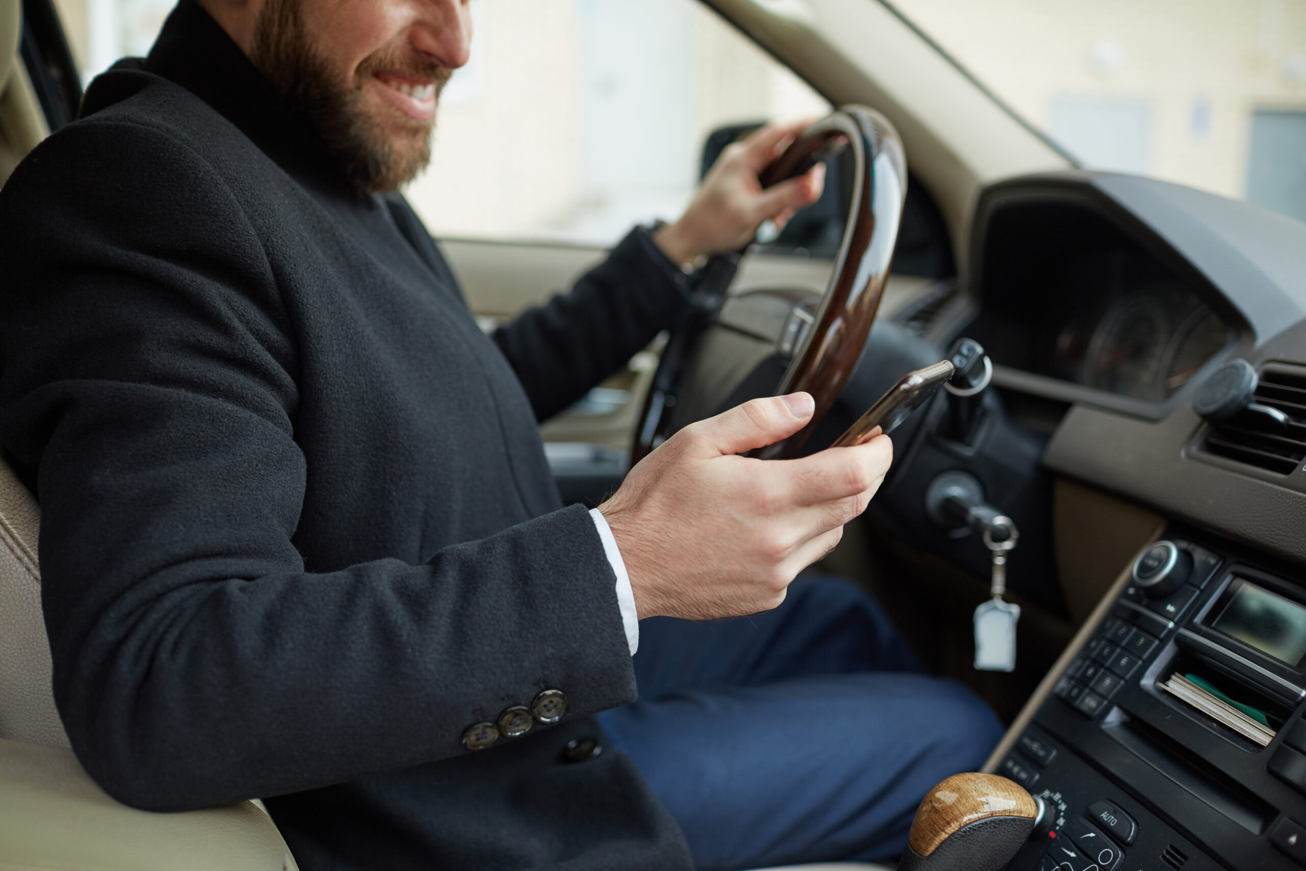 Man sitting in the car Young man sitting in the car and typing a text messaging on his mobile phone during driving