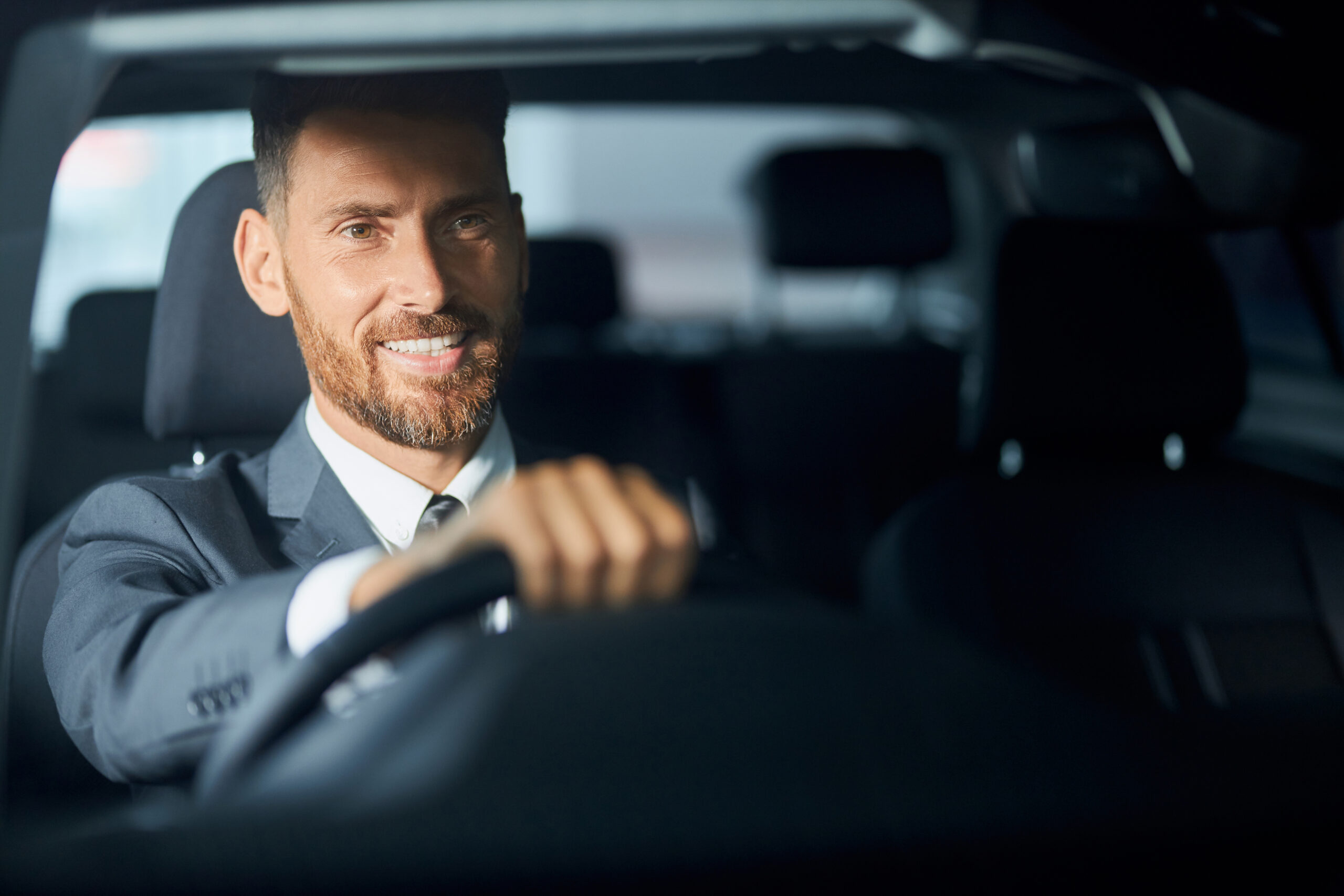 Smiling businessman in suit examining auto before purchase Smiling businessman in suit examining modern auto before purchase. Happy caucasian man buying new transport at showroom. Purchase and people concept.